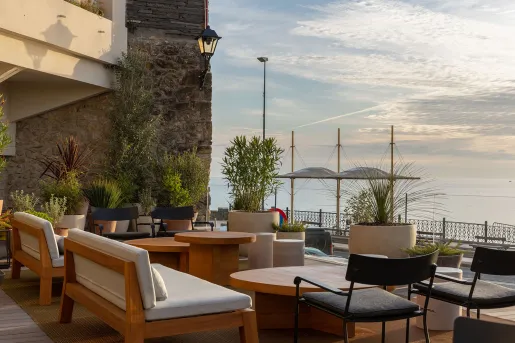 Outdoor patio and lounge area with cushioned seats, overlooking a lake to the right