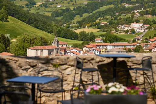 Stone barricade with tables and chairs, with a rustic town in the distance