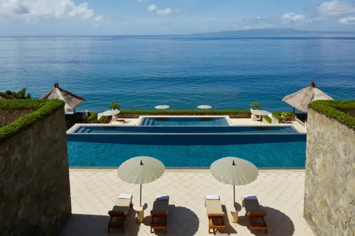 Lounge chairs by the pool looking out into the ocean
