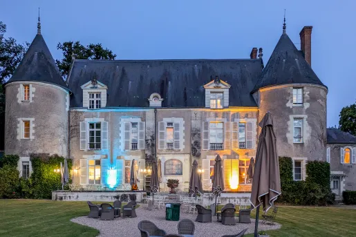 Exterior view of stone, castle-like building with blue and orange lights with a grass area in front