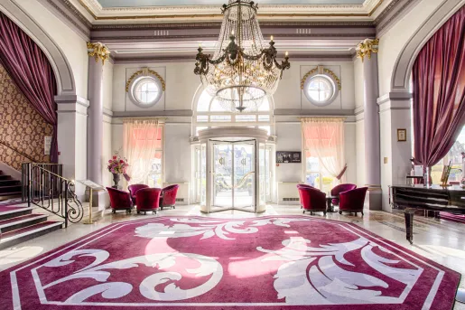 Hotel foyer with a red and white rug, and large chandelier