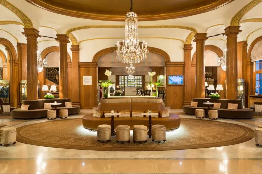 Indoor lobby with brown and tan leather sofas and a large chandelier in the center