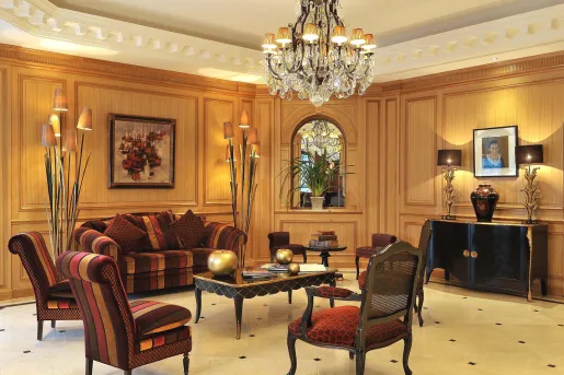 Indoor hotel lobby area with red-striped cushioned chairs and a chandelier
