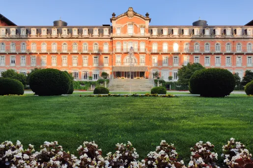 Exterior view of red building with a large staircase and a green grass field in front