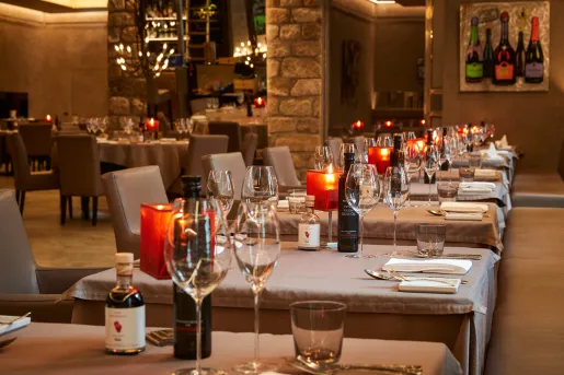 Indoor dining area with gray tablecloths and glasses of wine on each table