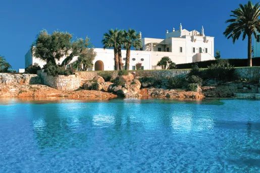 white building with palm trees next to ocean