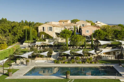 Outdoor hotel property view with an outdoor pool, surrounded by trees