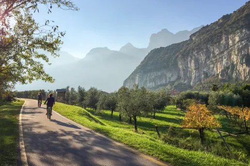 Two bikers on a road through grassy fields