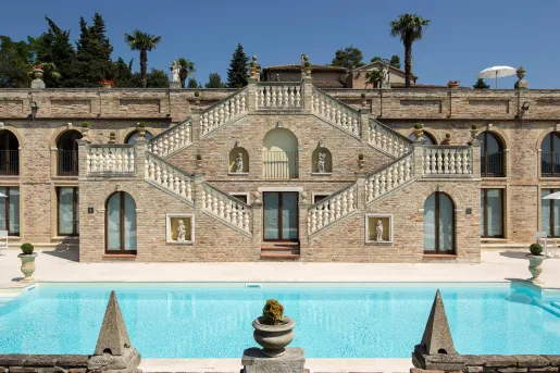 Exterior of stone building, with staircases on either side leading to an outdoor pool