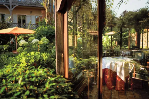 Indoor dining room with a large glass wall looking out to a garden