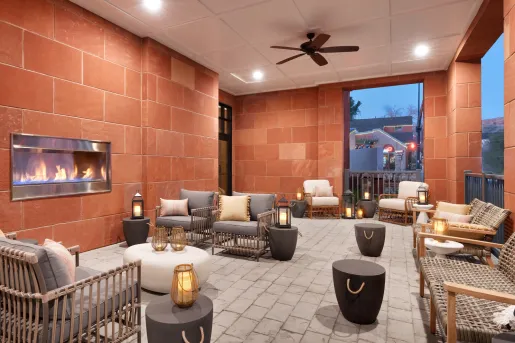 Indoor lobby with red stone walls, woven chairs and a fireplace in the wall