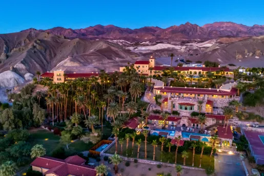 Exterior, sky view of tan and red hotel buildings, with tall palm trees and outdoor pool