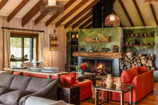 Indoor cabin lobby with red sofas in front of a green stone fireplace