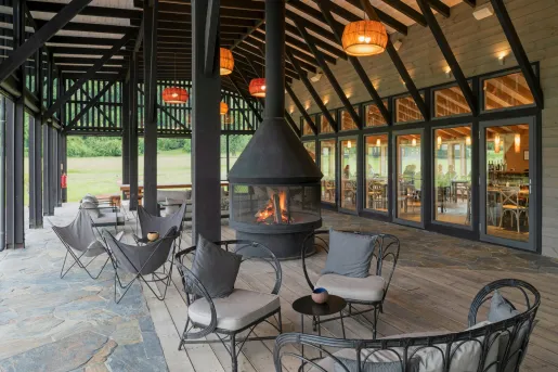 Outdoor seating area with a large, black fire pit, with black metal chairs surrounding it