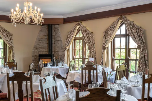 Indoor dining area with large, tan curtains over the windows and wooden chairs
