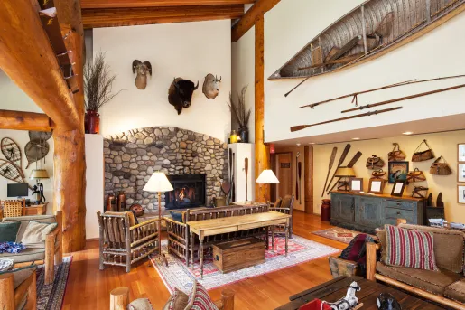 Indoor lobby with wooden pillars, a stone fireplace and animal heads on the wall
