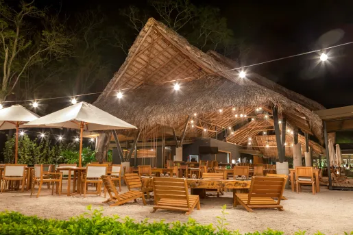 Outdoor hut with wooden chairs and tables on the sand