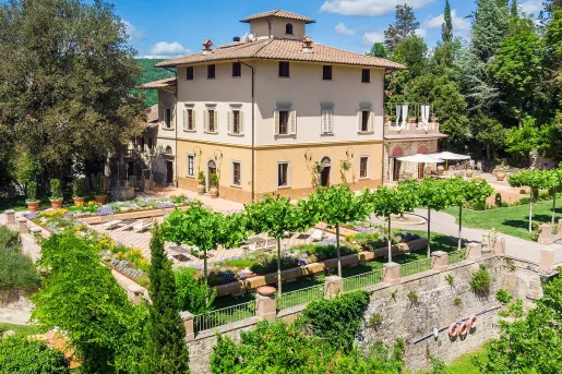 Yellow and white building with an outdoor courtyard, surrounded by trees and reclining chairs
