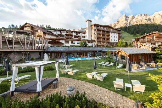 Exterior view of large, lodge-style hotel buildings with an outdoor pool and reclining lawn chairs