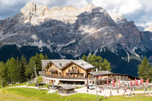 Outdoor view of hotel lodge with red umbrellas outside, with a large mountain in the background