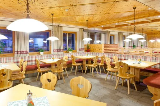 Dining area with wooden chairs and tables with windows along the walls