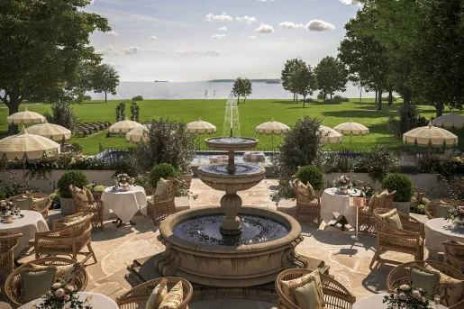 Outdoor dining area around a fountain, surrounded by a large area of grass