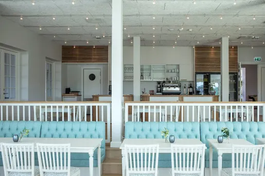 Kitchen with an espresso machine and turquoise blue couches and white chairs