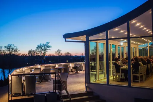Restaurant with large open windows and outdoor seating on a balcony