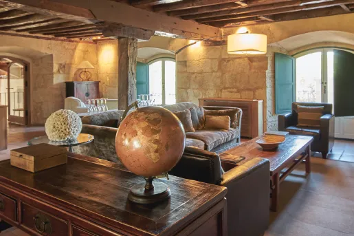 Indoor lounge with large, wooden pillars and wooden furniture, with a globe on the coffee table