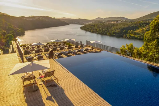 hotel pool with lounge chairs and a view of water
