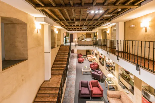 Indoor library with cushioned chairs and a stairway on the left