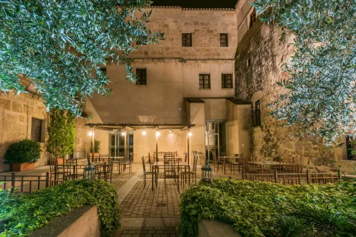 Outdoor dining area surrounded by trees and tall stone buildings