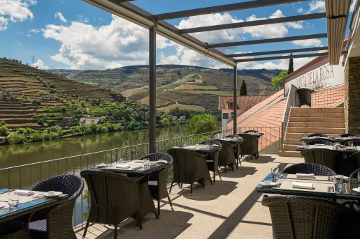 Outdoor dining area along a river with black chairs and tables