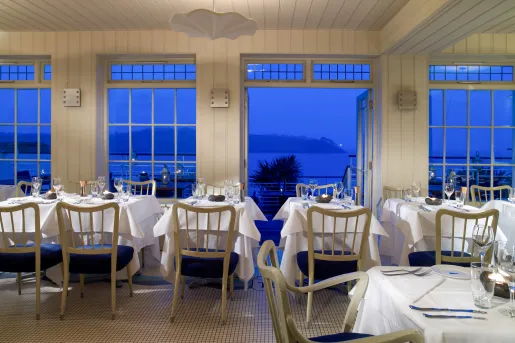 Indoor dining hall with open doors looking out to the ocean