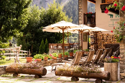 Outdoor patio with umbrellas and wooden chairs looking out to a garden