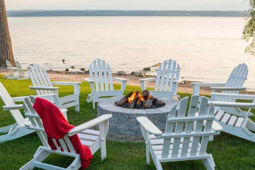 lawn chairs around a fire pit on the water
