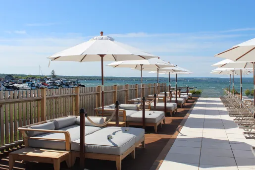 Gray, cushioned beds with umbrellas next to the ocean