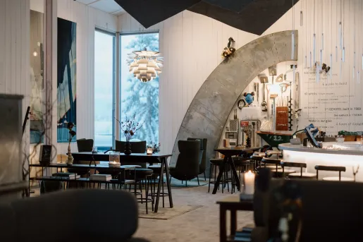 Indoor lounge with black tables and chairs with candles on each table