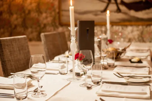 Indoor dining table with menus and candles on the table, surrounded by wine glasses