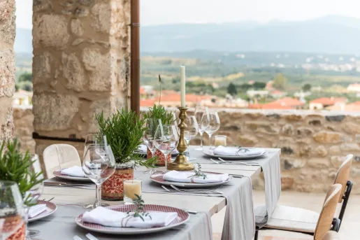Outdoor dining table with wine glasses, overlooking a small town