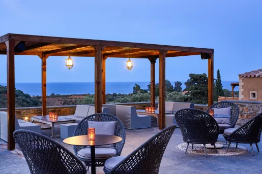 Outdoor lounge area with cushioned seats and wooden pillars