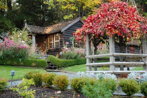 Wooden cottage surrounded by flowers and a stone pathway