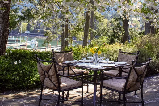 Dining table outdoors with glasses of wine and cushioned chairs