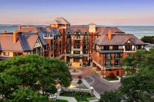 Outdoor view of red brick hotel building with a roundabout for cars outside