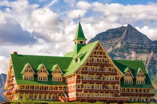Large hotel building with a green roof, with a mountain the background