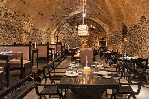 Indoor dining area with large, stone walls and light fixtures hanging from the ceilings