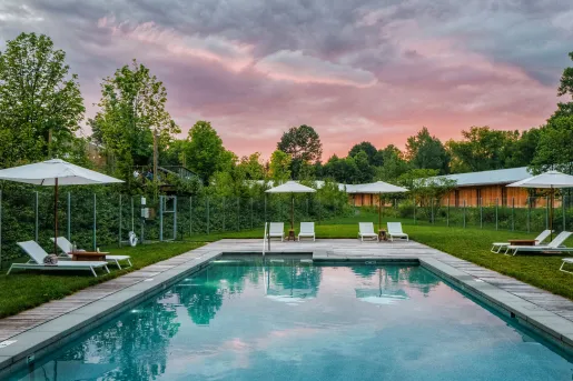 Outdoor pool surrounded by umbrellas and pool chairs