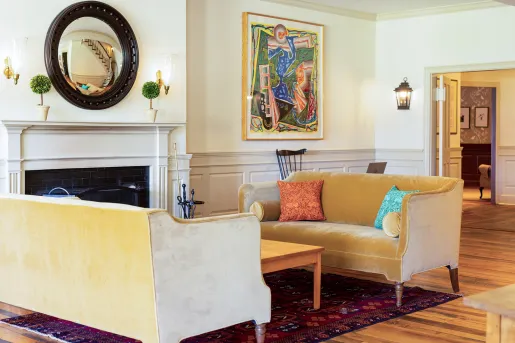Tan, velvet sofas in front of a stone fireplace with a large mirror above