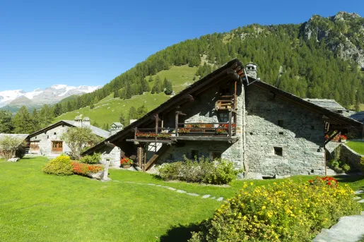Stone building with a wooden balcony with an open grass area in front