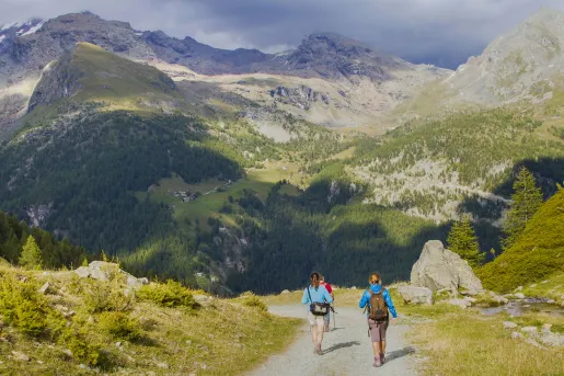 Three people descending a gravel trail on a mountain